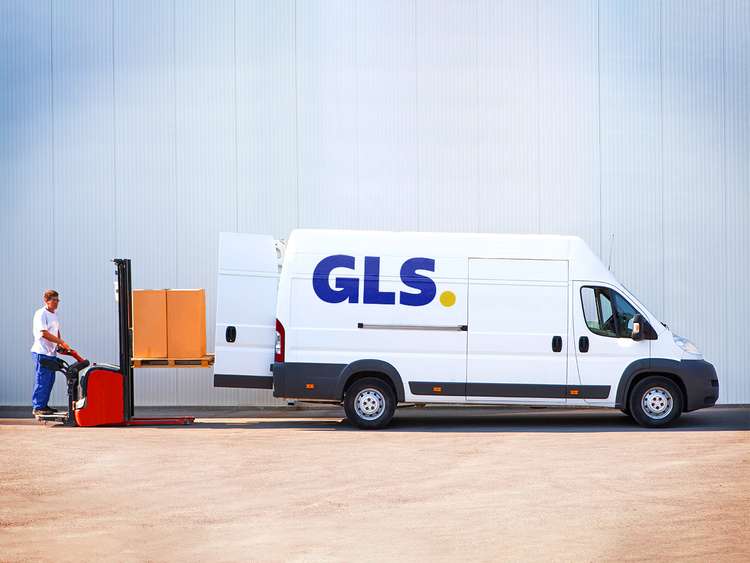 GLS-Zustellerin liefert ein Paket auf der Straße neben einem Lieferwagen aus