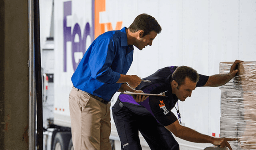 Operarios trabajan en el envío de un paquete grande y pesado.