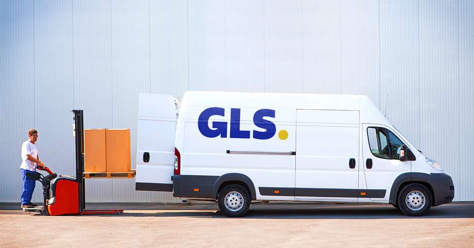 Kurier GLS doręcza przesyłkę i załadowuje przesyłkę do samochodu dostawczego.